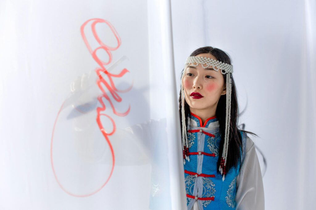 Asian woman in traditional attire painting on a white surface with elegance.